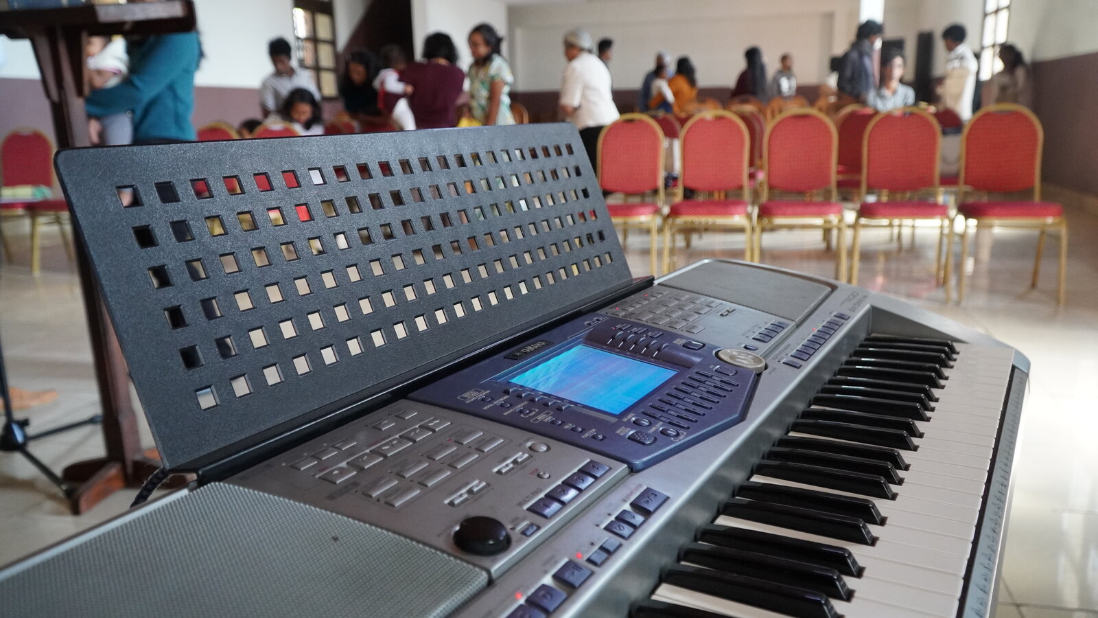 Keyboard on the chapel stage with members gathering after the Sunday service